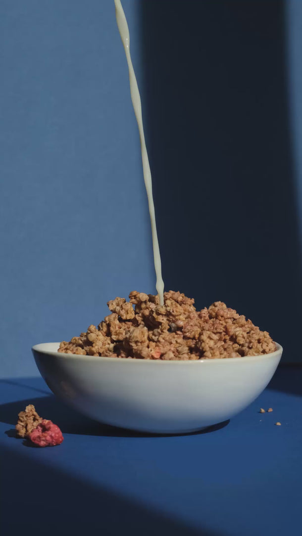 Haferdrink wird über eine Schüssel mit Granola gegeben