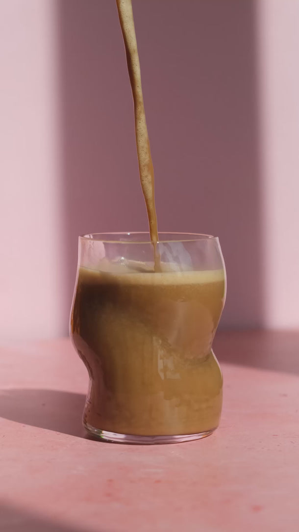 Cappuccino wird in ein Glas gegossen – das Glas füllt sich langsam.