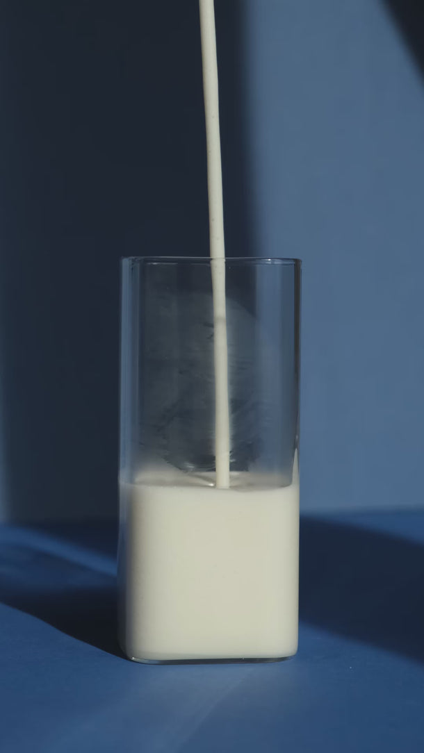 Haferdrink wird in ein Glas gegossen – das Glas füllt sich langsam.